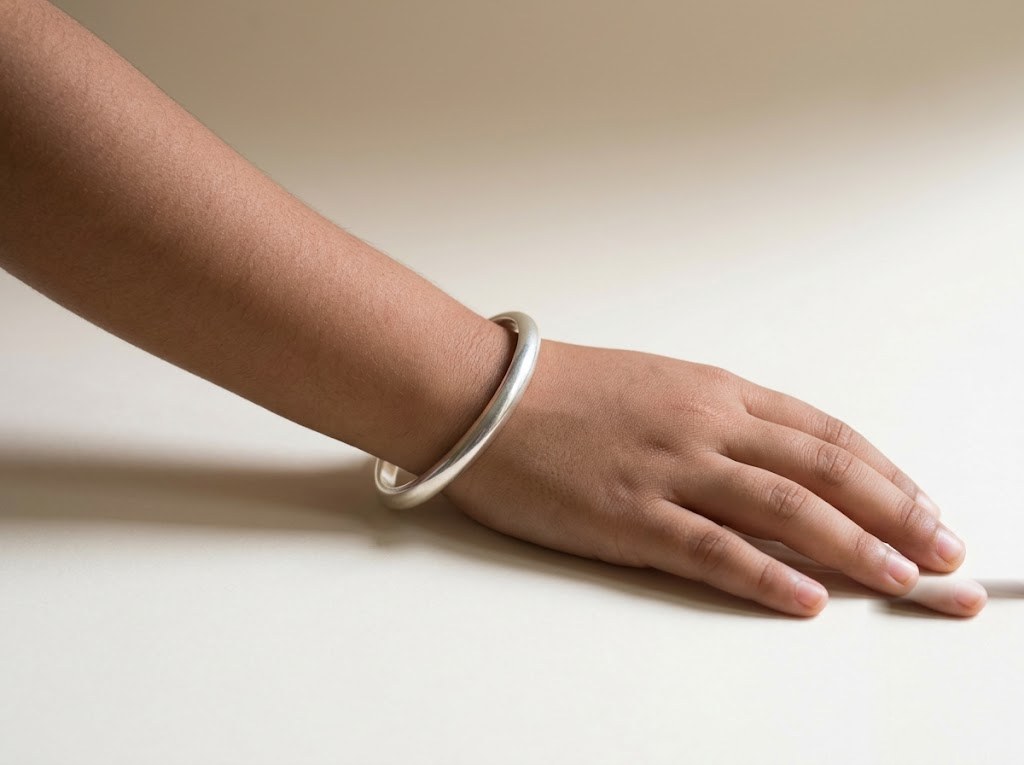 Plain smooth silver kada on the wrist of an Indian child