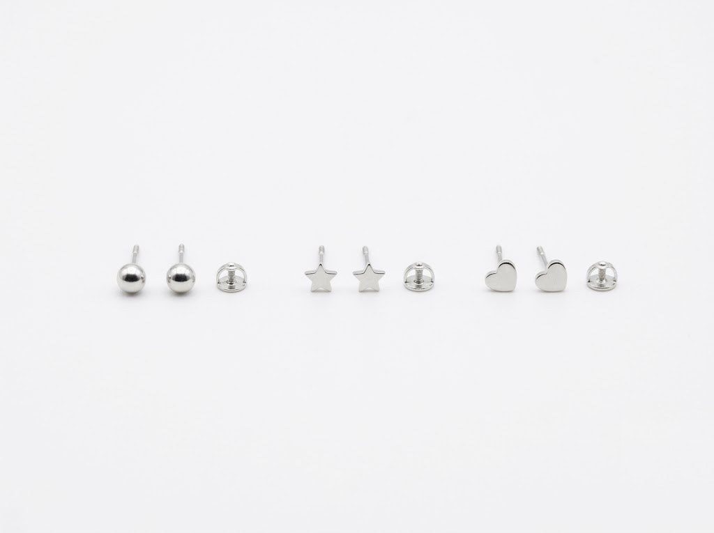 Three pairs of small silver stud earrings with screw backs, photographed on white
